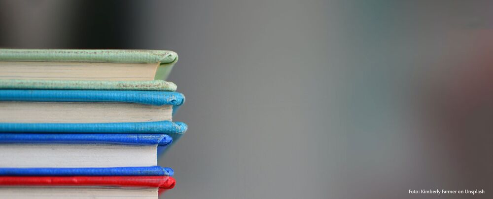 4 gestapelte Bücher am linken Bildrand