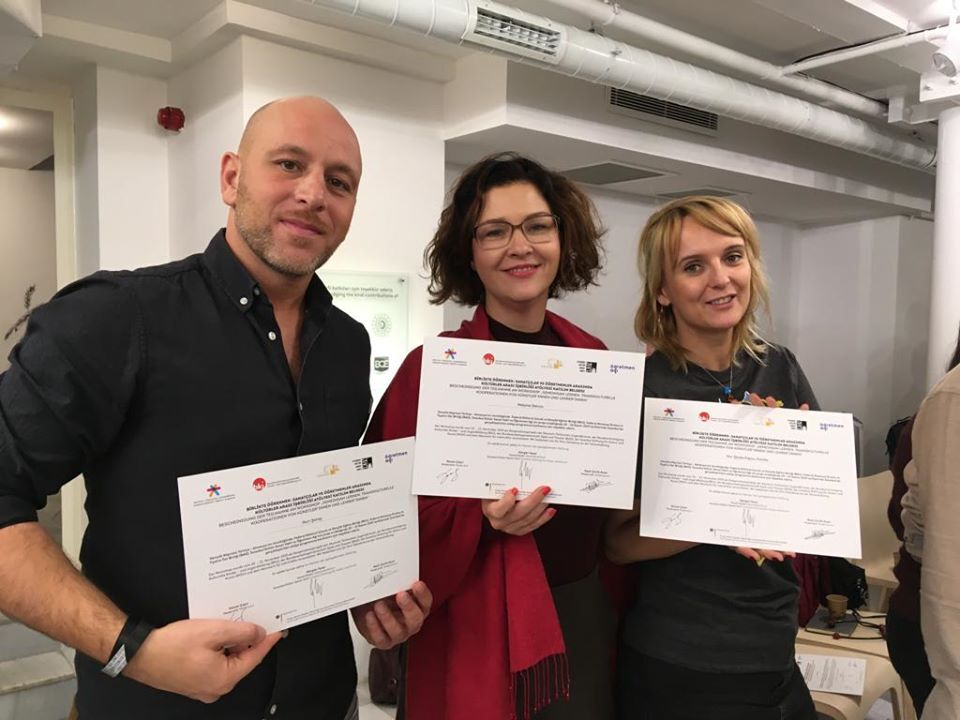 3 Menschen halten ihre Bescheinigung vor sich