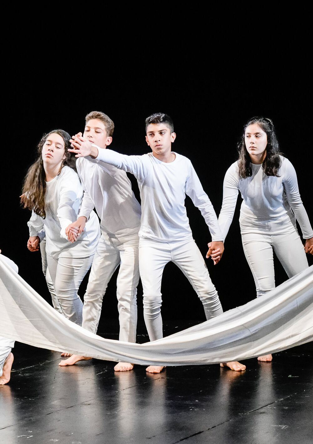 4 junge Leute in weiß gekleidet stehen vor einem gespannten weißen Tuch