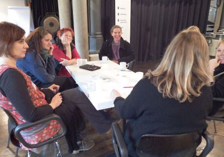 6 Frauen sitzen an einem Tisch und reden miteinander