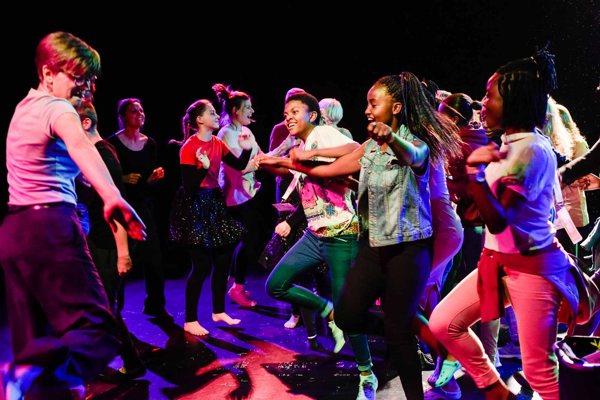 Mehrere Jugendliche tanzen fröhlich auf der Bühne.